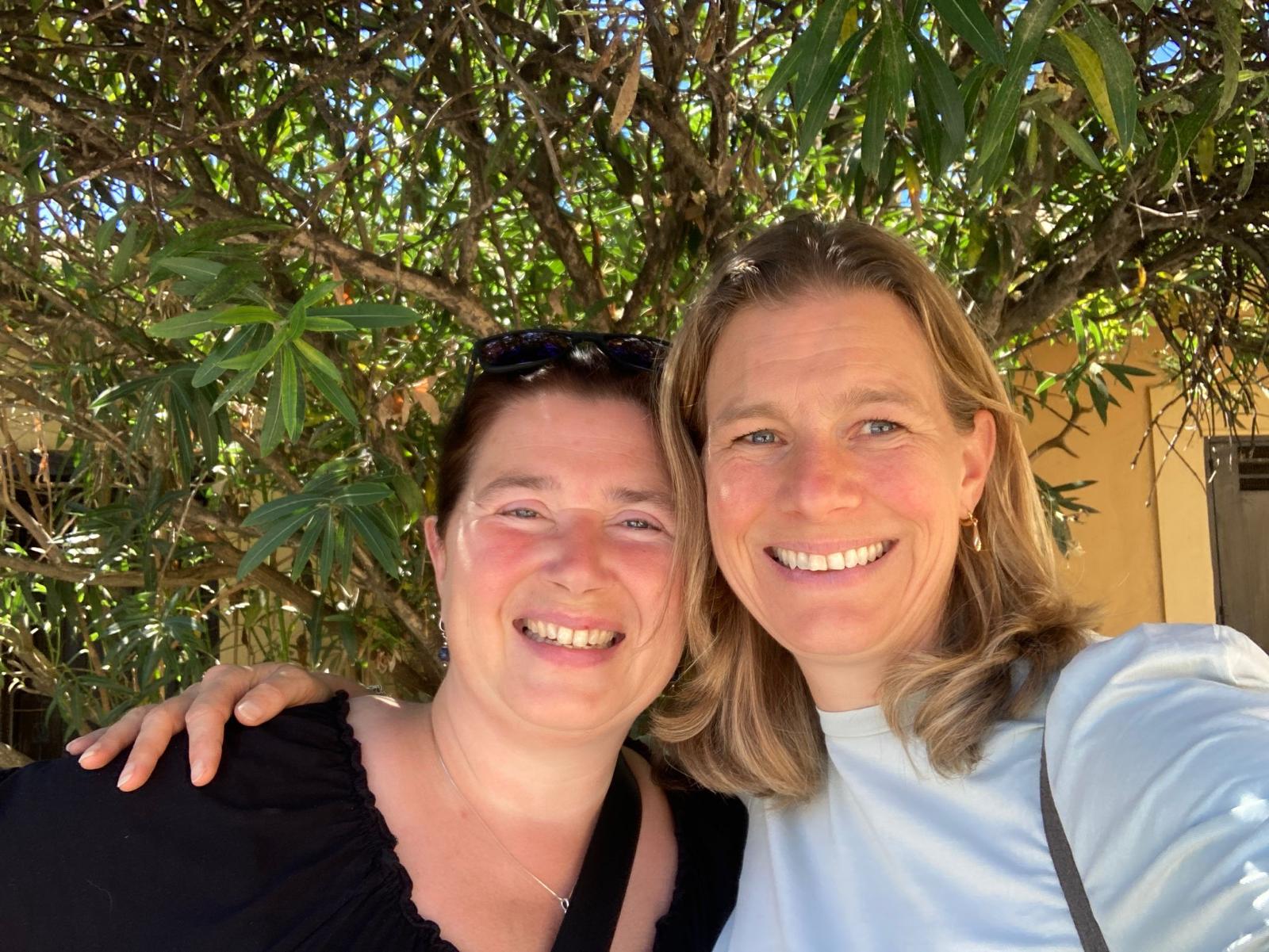 Twee vrouwen lachend samen onder de olijfboom