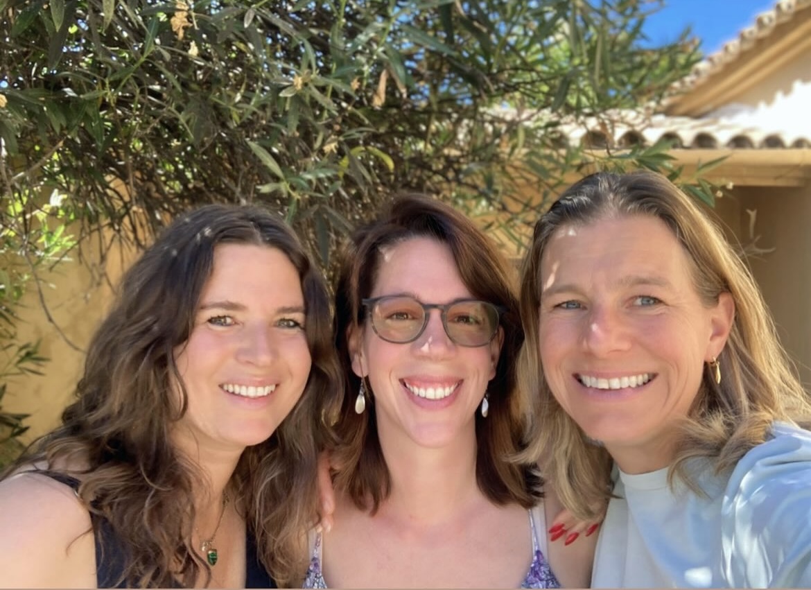 Drie vrouwen lachend samen in de tuin van de finca